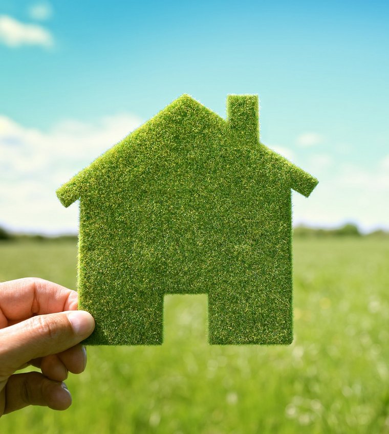 Grünes Haus aus Gras in einer Hand - spiegelt Nachhaltigkeit wieder